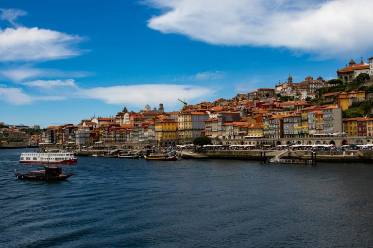 Colorful buildings rise along the hillside above the Douro River in Porto, Portugal, creating a picturesque scene that draws the attention of anyone moving to Portugal