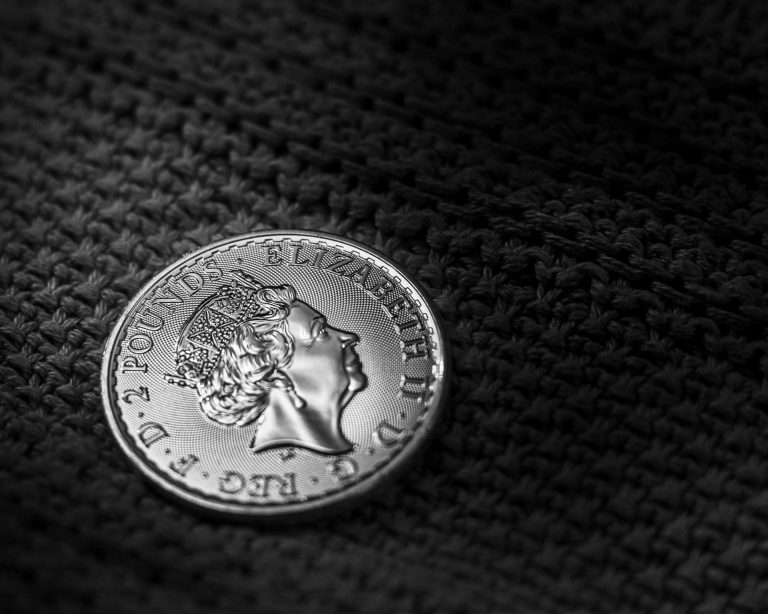 A close-up of a British two-pound coin featuring Queen Elizabeth II, placed on a textured dark surface, symbolizing cross-border savings considerations such as UK ISA accounts